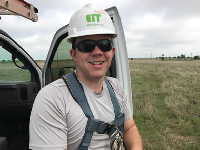 Technician working from a ladder on a building during a field service call.